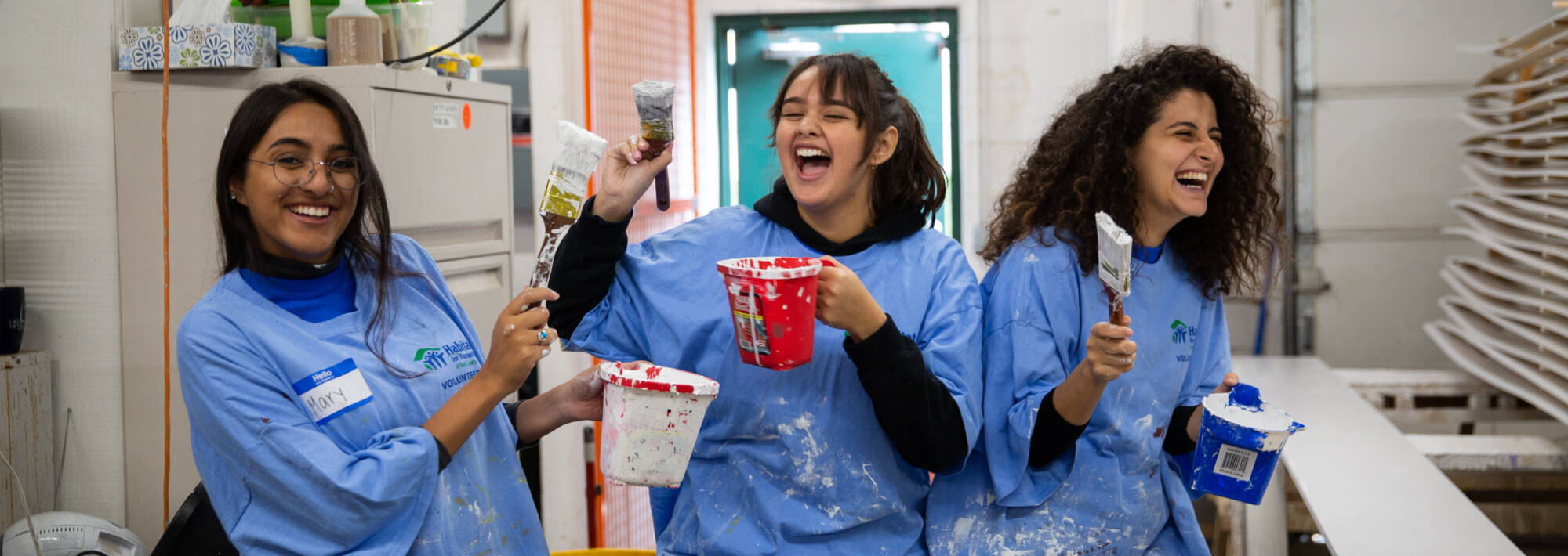 Three students participating in "Make a Difference Day" with painting at Habitat for Humanity